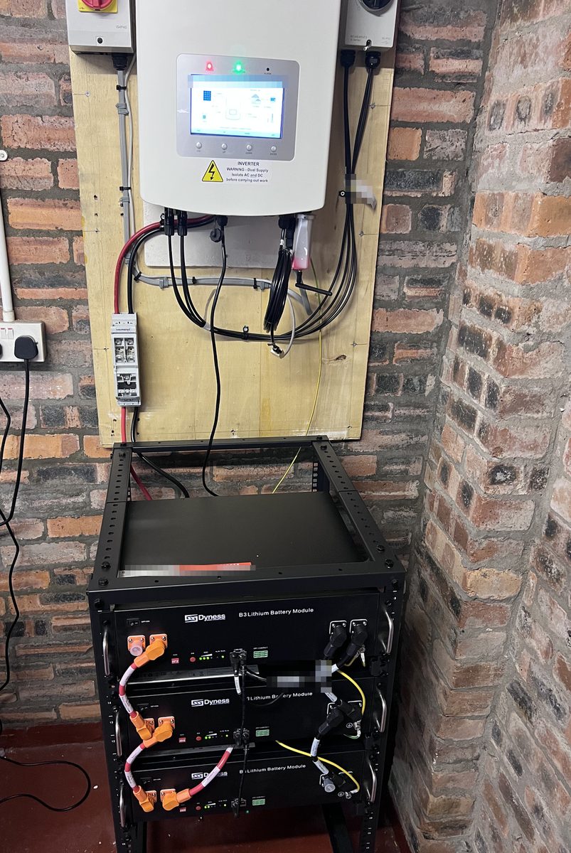 Three Dyness B3 modules in a rack below the Solis inverter on the garage wall